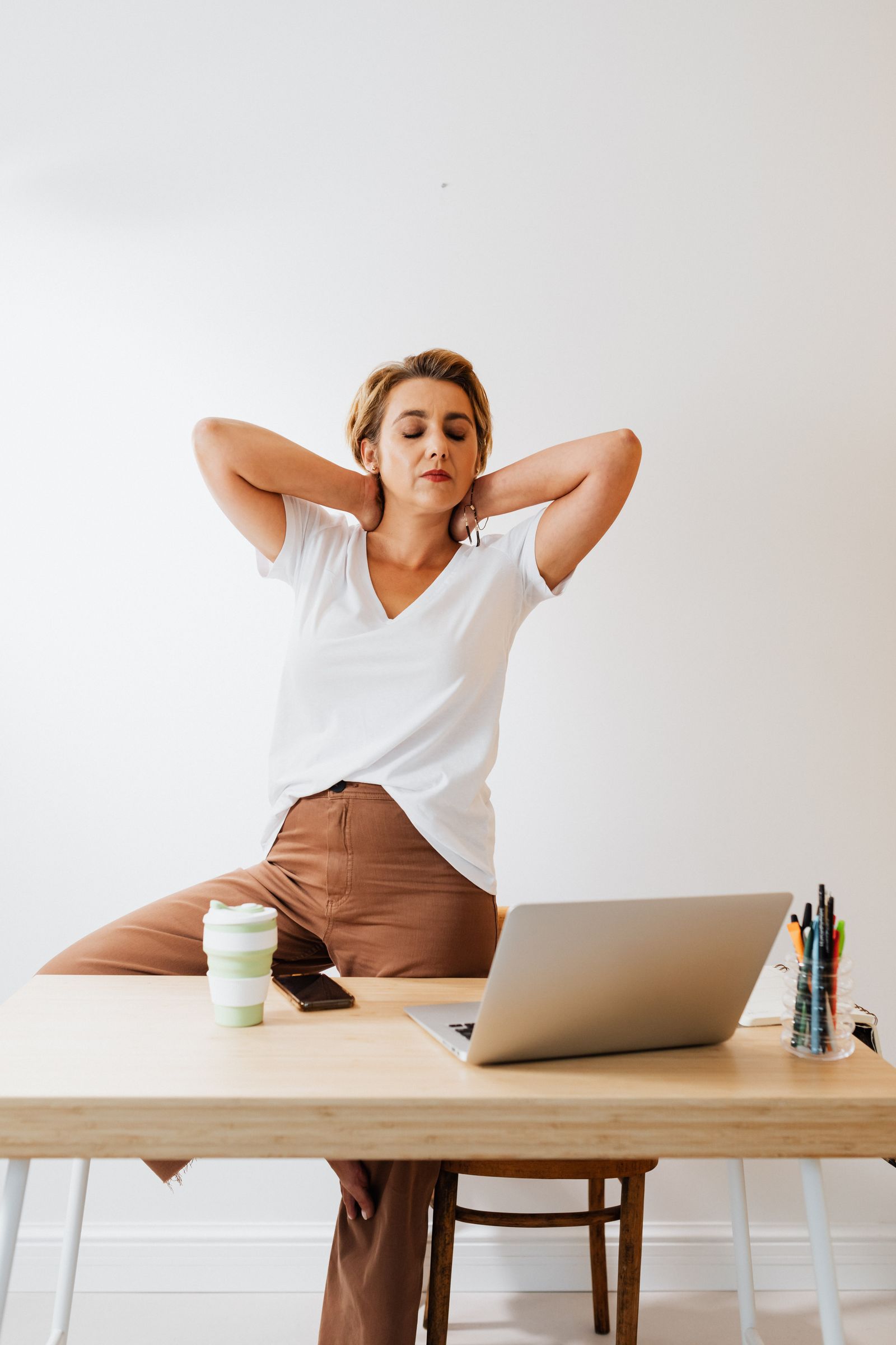 Person standing and stretching beside a desk